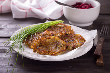 Potato fritters, beet salad, green onions on a wooden surface