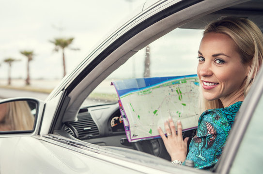 Pretty young woman sitting in car with a roads map