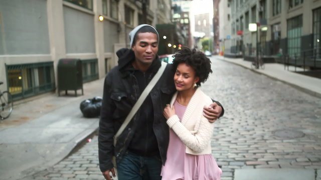 A cute couple walk with each other down a pretty city street