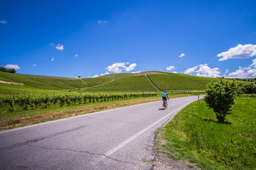 Ciclista pedala su strada nelle colline delle langhe