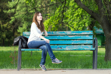 Young beautiful woman sitting on bench in park