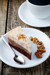 Tasty nuts cake with cup of coffee on wooden background.
