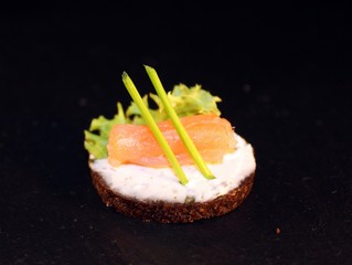 Lachsröllchen auf einer Pumpernickel Scheibe