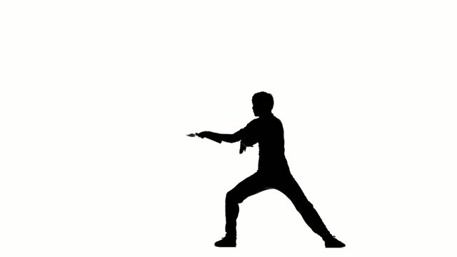 young karate man expertly twirling nunchaku, silhouette 