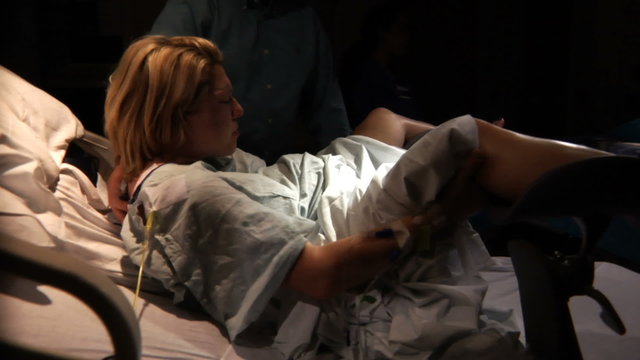 Woman lays in hospital bed and gives birth.