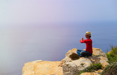 young man doing yoga in mountains