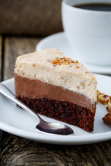 Tasty nuts cake with cup of coffee on wooden background.