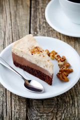 Tasty nuts cake with cup of coffee on wooden background.