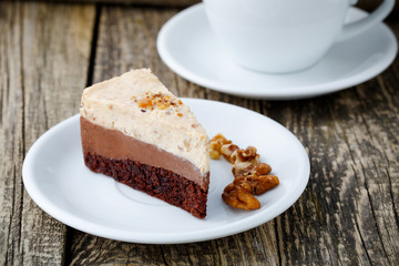 Tasty nuts cake with cup of coffee on wooden background.