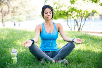 Fitness woman meditating on the green grass