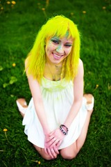 Beautiful hipster young woman with yellow hair sits on grass