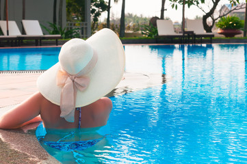 Woman  with hat  from back in  swimming pool