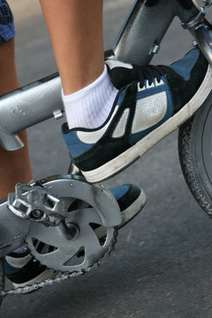 Foot with sneakers on pedal of bicycle
