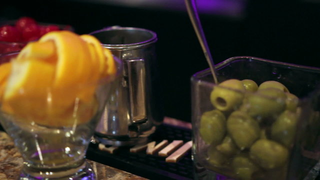 Several glasses filled with cocktail garnishes on a bar.