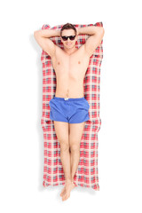 Fototapeta premium Handsome young man sunbathing on a mattress