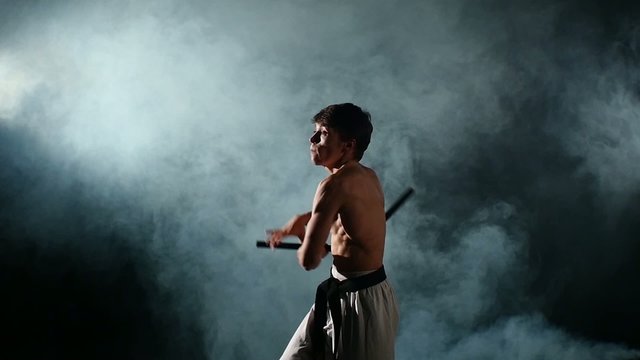 Karate man with a naked torso exercise with nunchaku. Slow