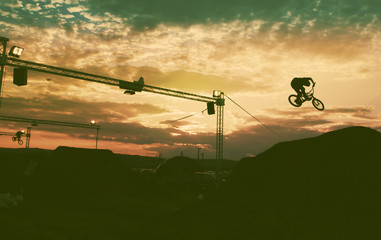 Silhouette of a man doing a jump with a bmx bike against sunset