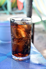 Glass of cola with ice on the table