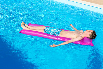 Teenage boy lying on air mattress in swimming pool