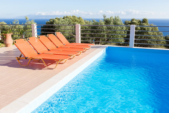 Row of orange loungers near blue swimming pool