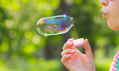 Lips blowing big soap bubble outdoor