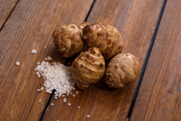 jerusalem artichoke with salt on raw wooden table