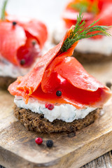 Sandwich of black bread, cheese with herbs and red salmon.