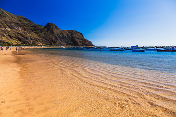 Beach with waves on sand and mountain