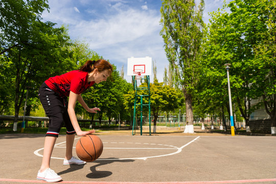 Athletic Woman Dribbling Basketball At Mid Court