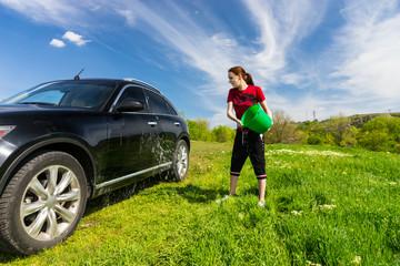 Woman Washing Car with Bucket of Water in Field
