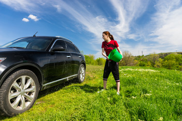 Woman Washing Car with Bucket of Water in Field