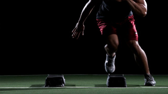 An African American athlete works on speed and agility while doing box jumping