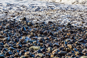 Stones in white foam on the beach