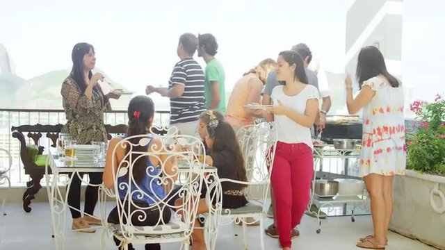 Many generations talking and eating at a Brazilian family BBQ