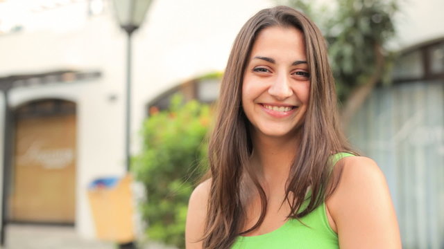 A cute young woman laughs and smiles into camera