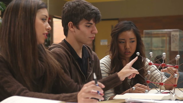 College students study course material in a group at a table filled with books