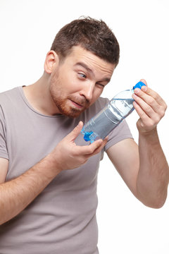 young smiling man carefully consider water bottle