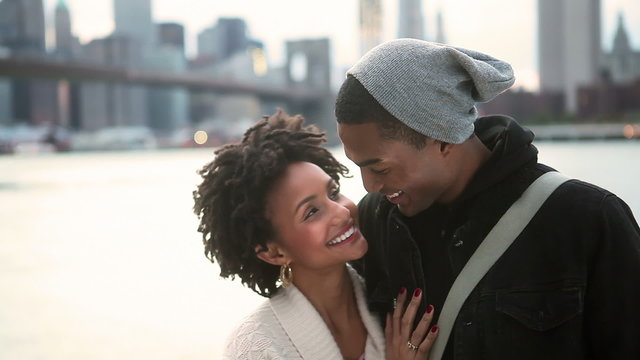 A good looking young couple stand together smiling and looking at the camera