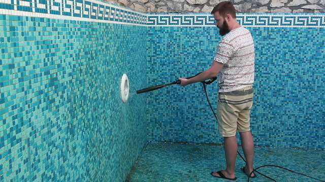 A man is cleaning the pool wall 