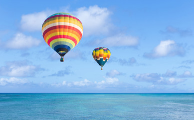 Naklejka premium Hot air balloon over ocean and clouds blue sky