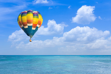 Fototapeta na wymiar Hot air balloon over ocean and clouds blue sky
