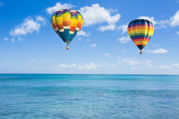 Hot air balloon over ocean and clouds blue sky