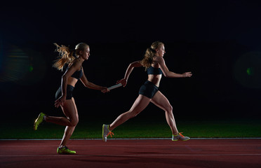 athletic runners passing baton in relay race