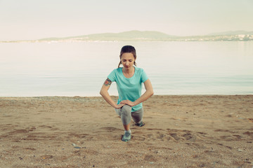 Woman stretching her legs before running on beach