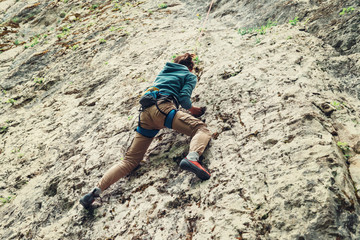 Active young woman climbing on rock