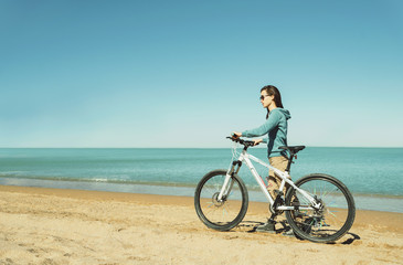 Fototapeta na wymiar Girl walking with a bicycle on beach