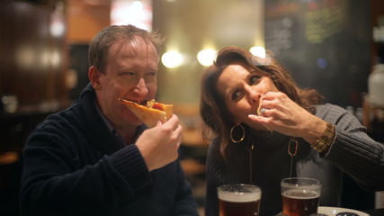 A couple cheering their pizza in the city at night