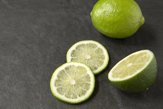 Fresh limes on slate background