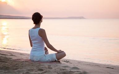 Fototapeta na wymiar Young woman meditating near the sea