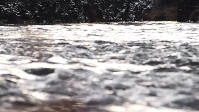 Close up abstract view of rushing water flowing down the river in winter, in slow motion